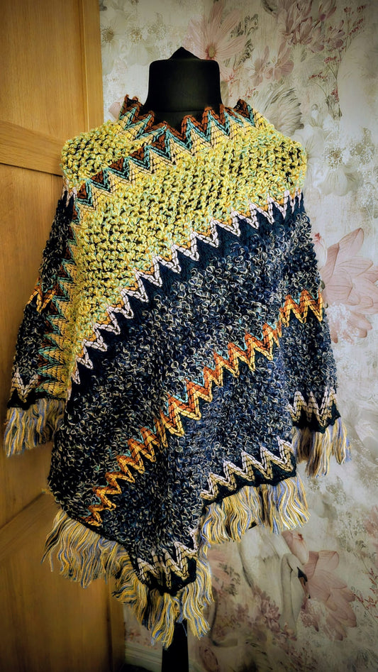 Colorful knitted poncho on a mannequin against a textured wall.