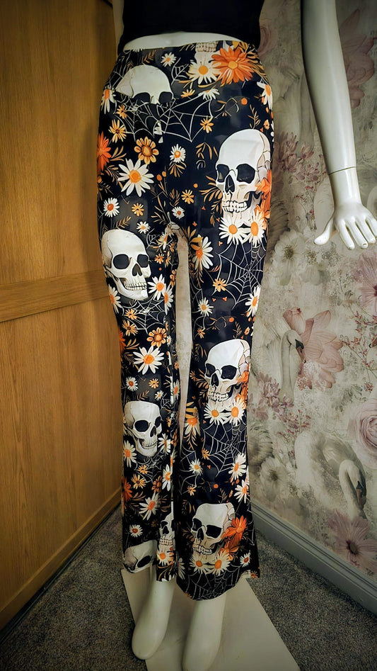 Floral and skull patterned pants on a mannequin against a floral wall.