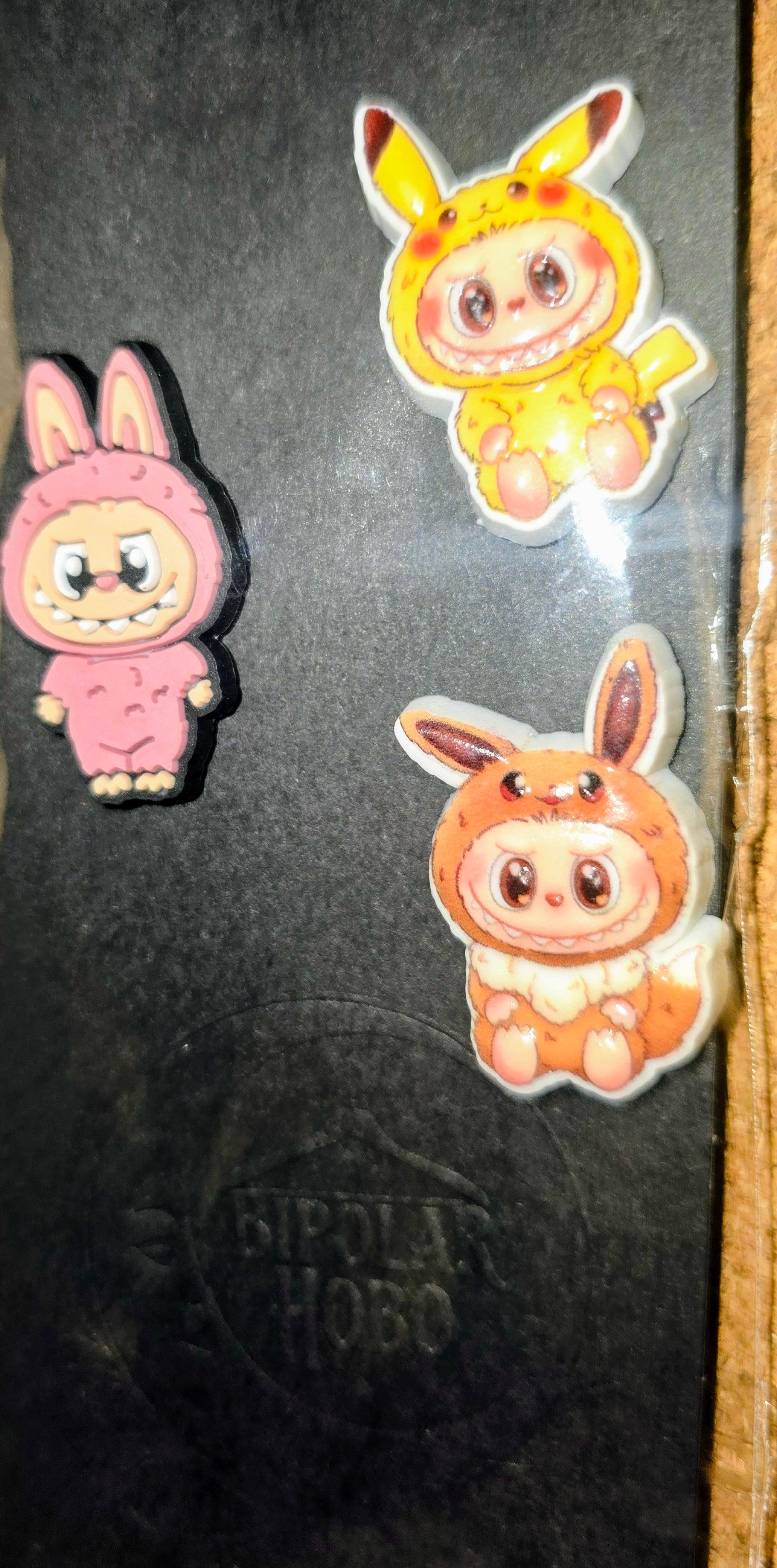 Three cartoon character pins on a dark surface