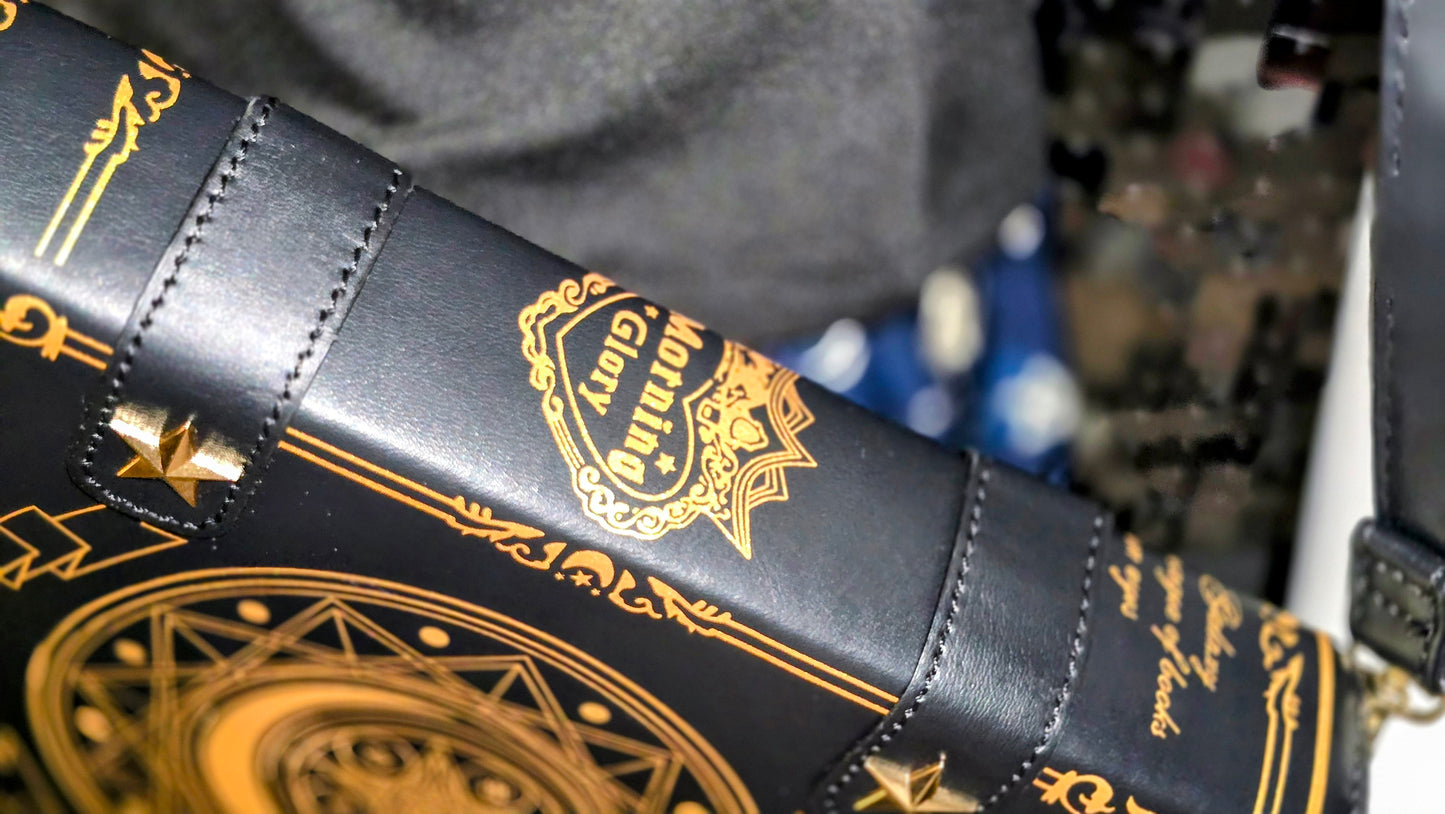 Black leather bag with gold embroidery and designs, featuring a brand logo.