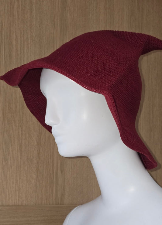 Maroon knitted hat on a mannequin head against a wooden background