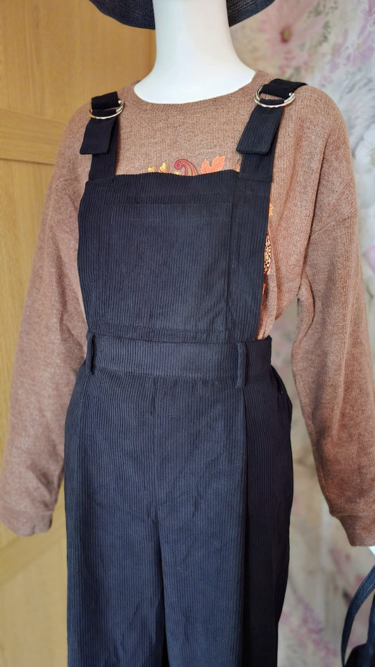 Mannequin wearing a brown sweater and black pinstripe overalls against a neutral background