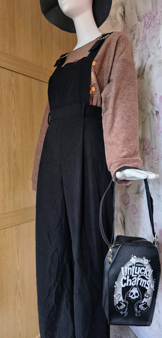 Mannequin wearing a black outfit with a pink sweater and black bag featuring white text.